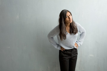 Young indian woman against a grunge wall very angry and upset, very tense, screaming furious,...