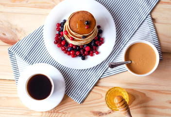 Flat  lay with pancakes, honey, peanut paste and coffee.
