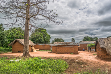 View of traditional village, thatched and zinc sheet on roof houses and terracotta brick walls, cloudy sky as background
