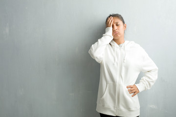 Young sporty indian woman against a gym wall worried and overwhelmed, forgetful, realize something,...