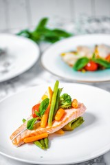 steamed salmon steak with vegetables on a white marble table
