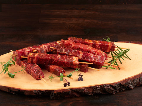 Raw Fresh Beef And Lamb Skewers, Uncooked, On A Wood Board, Garnished With Fresh Pea Shoots And Rosemary Sprigs