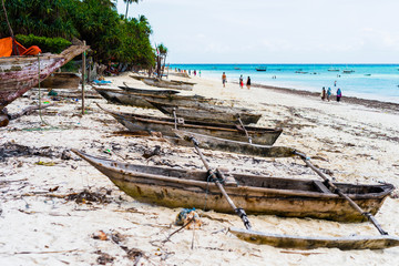 Fototapeta na wymiar old wooden fishing boats with paddles on a beach of fishing village in Zanzibar