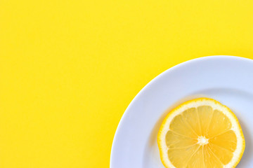 Top view of a plate with sliced lemon on a yellow background.