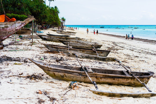 old wooden fishing boats with paddles on a beach of fishing village in Zanzibar