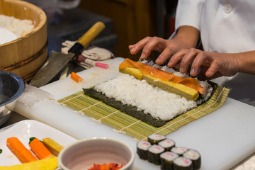 Sushi chef prepares maki rolls