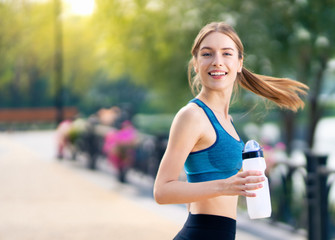 Happy woman with bottle of water, during morning jogging