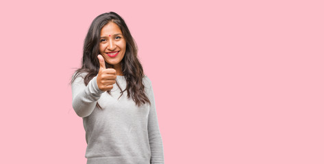 Portrait of young indian woman cheerful and excited, smiling and raising her thumb up, concept of success and approval, ok gesture