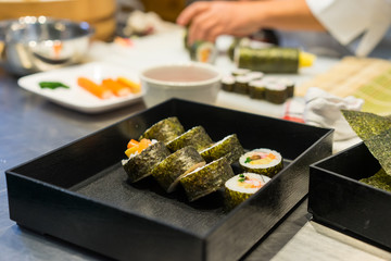 Sushi chef prepares maki rolls