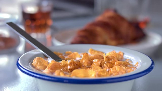 some honey pouring on corn flakes in bowl with milk