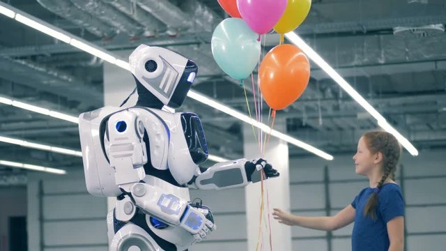 A child gives balloons to a white robot, close up.