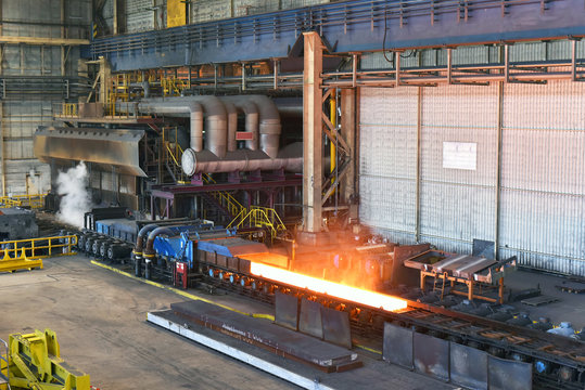 machine with conveyor belt with glowing metal frame in the production line of a steel mill // Herstellung von Stahl im Walzwerk - gl&uuml;hende Bramme auf dem Fliessband 