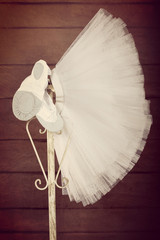 Pointes female ballet shoes with skirt tutu hanging on the stand, close up vintage view