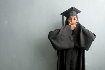 Young graduated indian woman against a wall covering mouth, symbol of silence and repression,...