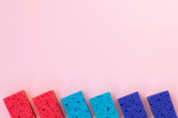 Six colorful sponges lying on pink background