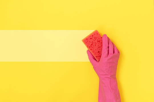 Woman holding sponge for washing in her hands against yellow background