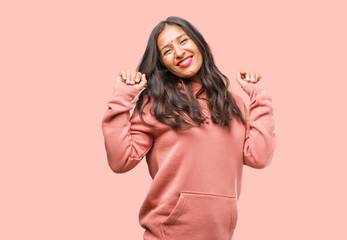 Portrait of fitness young indian woman listening to music, dancing and having fun, moving, shouting and expressing happiness, freedom concept