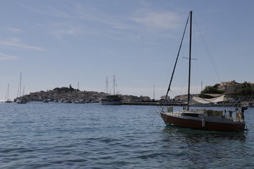Fototapeta premium Sailboats, yachts on the Adriatic Sea. Beautiful weather. Sunny, hot, summer day on the Croatian coast. ​​Primosten in the background. Rocky shore, mediterranean vegetation, seashore, Croatia