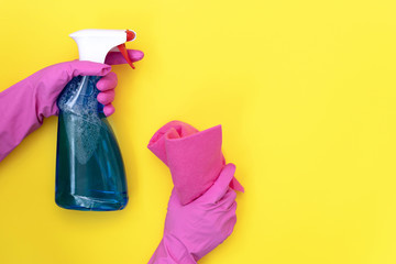 Woman holding cleaning towel and detergent spray bottle on yellow background