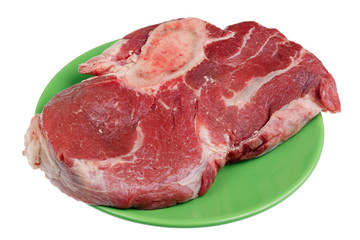 The big raw  beef stake with blood and a bone on green ceramic plate isolated