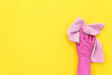 Woman holding cleaning towel in her hand against yellow background