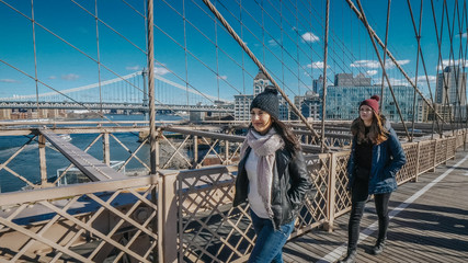 Two girls walk over the famous Brooklyn Bridge in New York