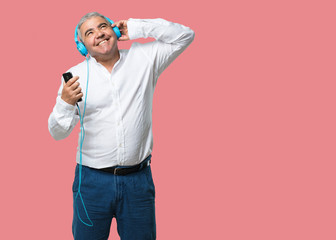 Middle aged man happy and fun, listening to music, modern headphones, happy feeling the sound and rhythm