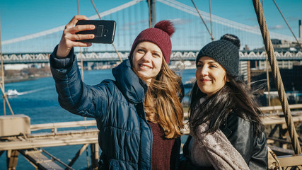 Fototapeta na wymiar Two friends in New York walk over the famous Brooklyn Bridge