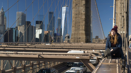 Beautiful girl on Brooklyn Bridge enjoys a sunny day while relaxing