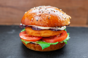 Tasty grilled prawn and beef burger with lettuce and mayonnaise served on pieces of brown paper on a rustic wooden table of counter, with copyspace