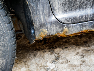Rust detail close up shot on old black car on a bright sunny day.