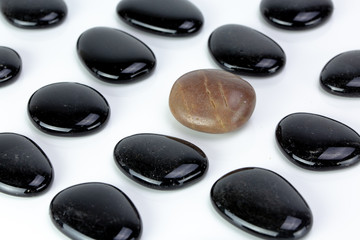 Black pebbles on white background with brown pebble.