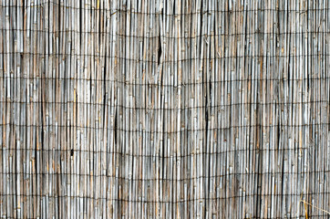 Close-up  of old banded with steel wire peeled reed fence . Backyard reed fencing. Yard privacy and...