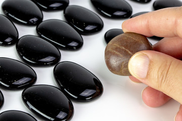 Black pebbles on white background with brown pebble.
