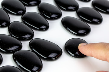 Black pebbles on white background with brown pebble.