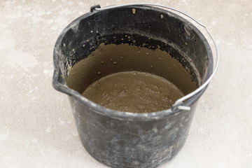 dark bucket. This is the solution for leveling the floor. on the background of the biton floor, and poured out of it