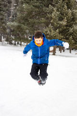 Fototapeta na wymiar Little boy jumping on a snowy field