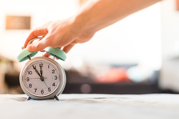 Man is pushing an alarm clock in the morning, sunshine and blurry background