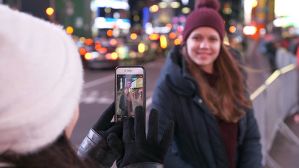 Two girls in New York take photos at Times Square