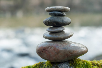 Closeup of stone balance on rock covered by moss in border river
