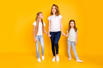 Fototapeta premium Full length body size view portrait of three nice cute winsome attractive slim cheerful people holding hands mum mommy isolated over bright vivid shine yellow background