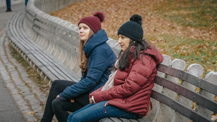 Two girls in Central Park New York sit on a bench to relax