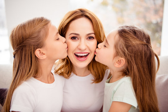 Close-up portrait of nice cute lovely winsome sweet gentle tender attractive charming cheerful cheery positive glad redhair people mom kissing pre-teen girls in house indoors