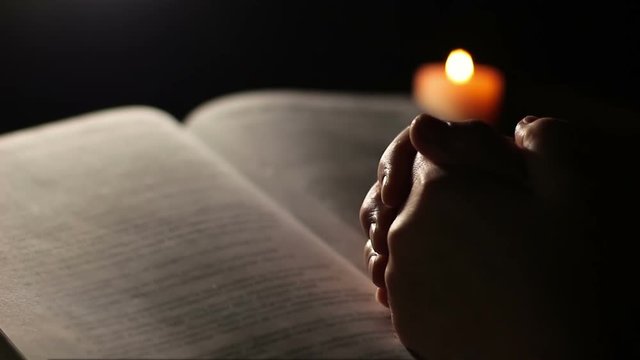 Hands holding, praying on open Bible book. Hands of an old woman on an open book. The concept of reflection and meditation
