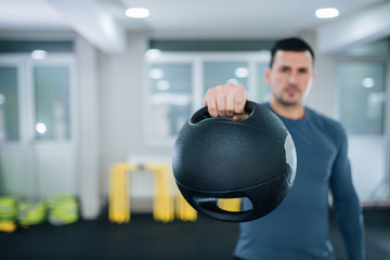 Strength training concept. Man holding dual grip medicine ball, focus on the foreground, on the ball.