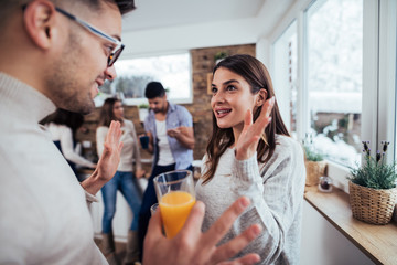 Two young couples on winter vacation indoors in the morning. Roommates talking on winter morning at home.