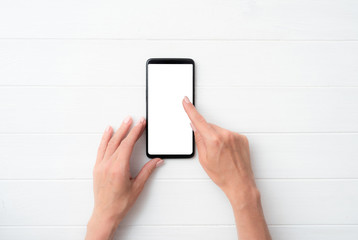 Mock up of user hands with black smartphone on white table for your design