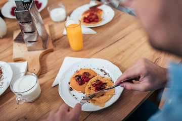 Man eating homemade pancakes with berries.