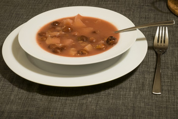 Traditional hungarian cherry soup with apple and carrot in a bowl on a table.