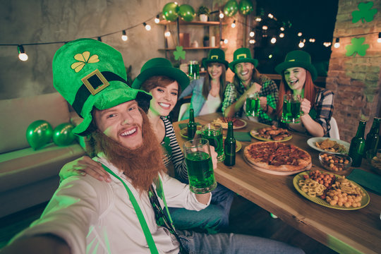 Group buddies hands arms beer table pizza chips meat national culture costumes tradition leprechaun hats casual checkered plaid jeans shirts lucky beard laugh laughter make take selfies wink blink